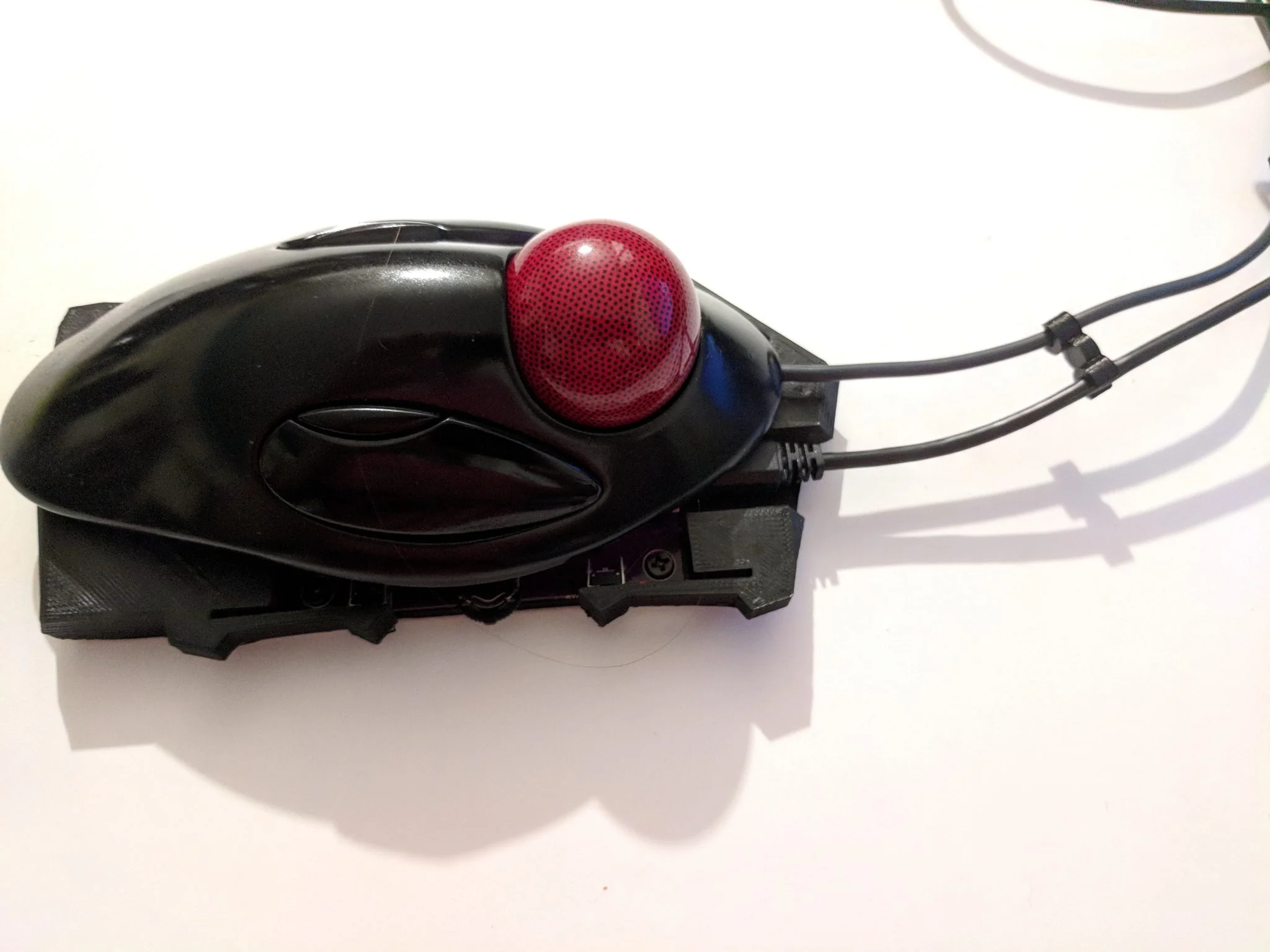 Track-ball sitting on top of the mousetrap I designed, with my radial cable organizer cleaning things up